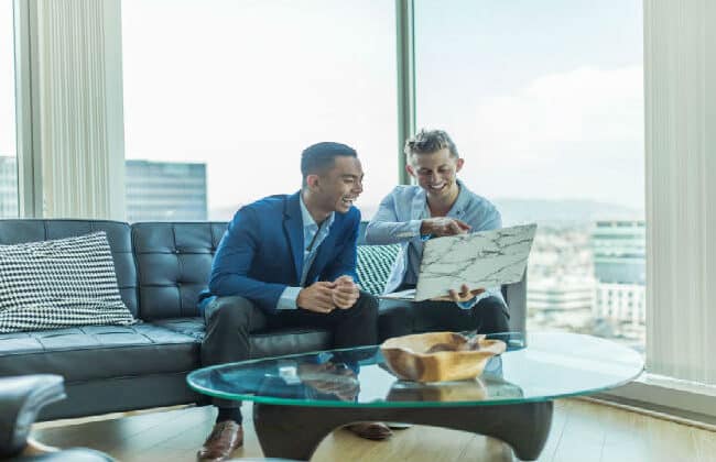 Two business men smiling at a screen on a laptop