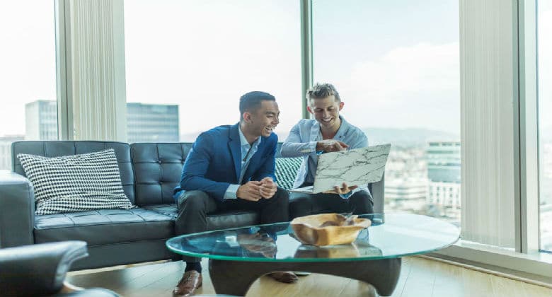 Two business men smiling at a screen on a laptop