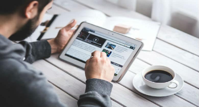 Man looking at Tablet while at a coffee shop