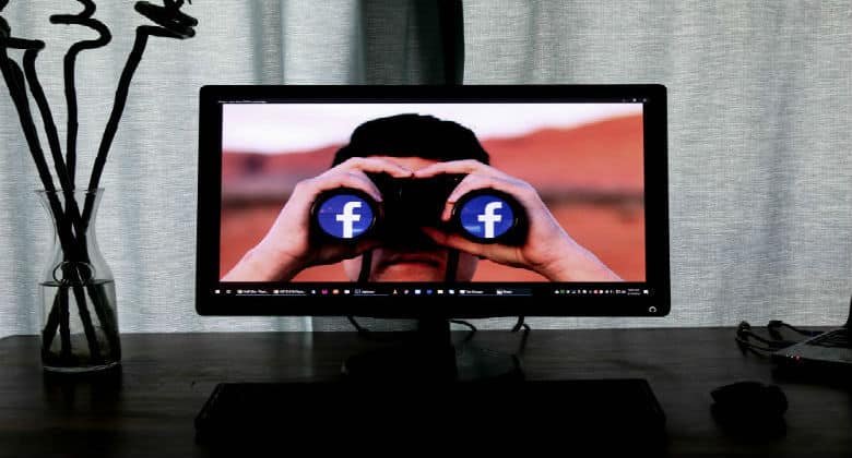 Man on a screen looking through binoculars and seeing Facebook
