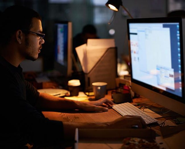 A male web developer working on his desktop during the night