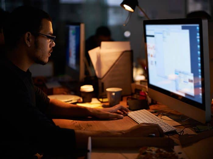 A male web developer working on his desktop during the night