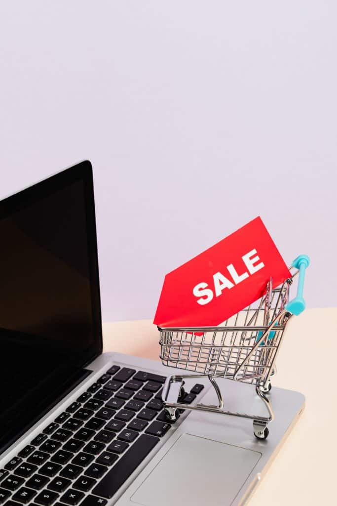 eCommerce Sales - Small shopping cart with sales sign in it on a laptop