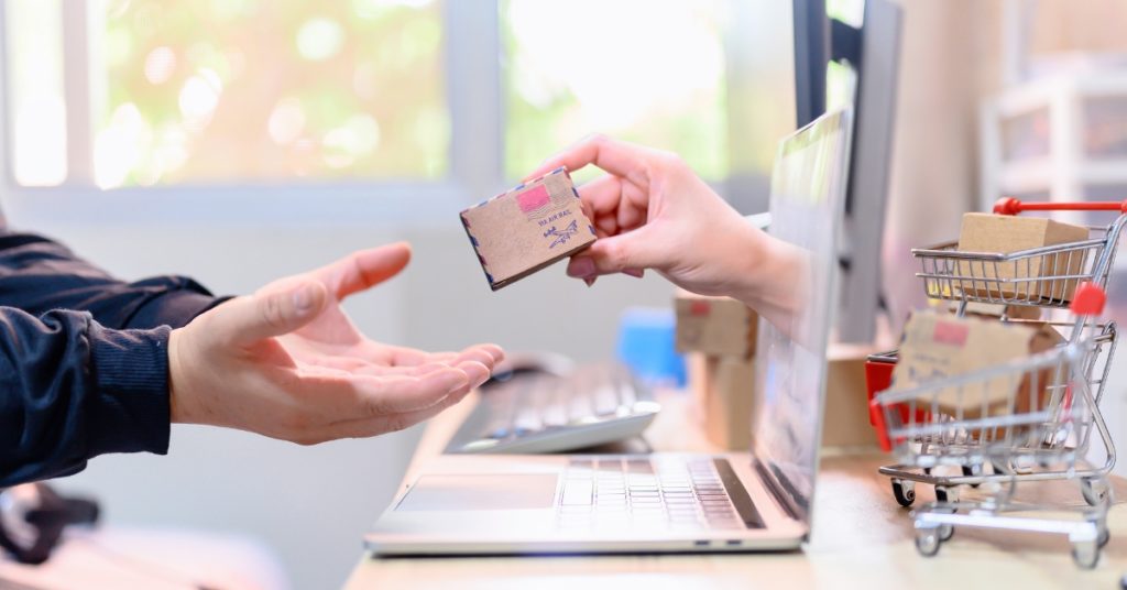 Interpretation of online shopping - Man reaching for delivery through computer screen next to shopping cart